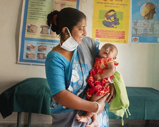 Woman in India holding new baby in healthcare setting
