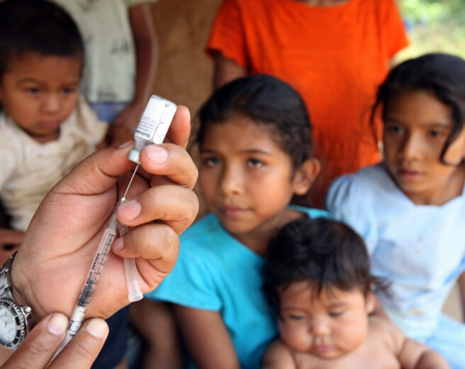 Medical professional preparing vaccine shot in-front of children